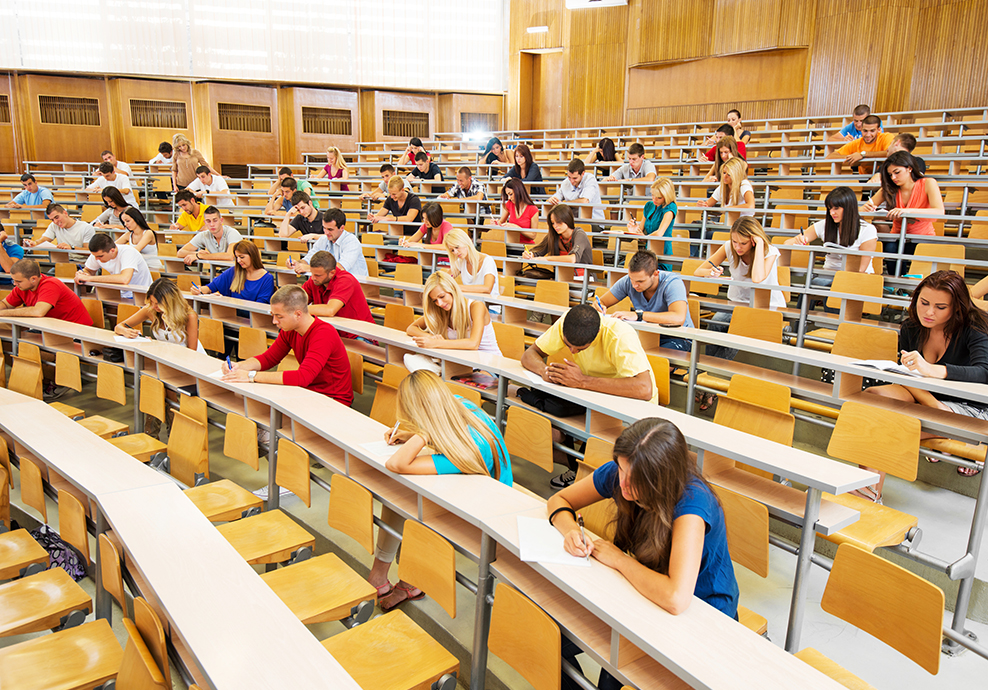 Group of college students inside a large auditorium taking an exam